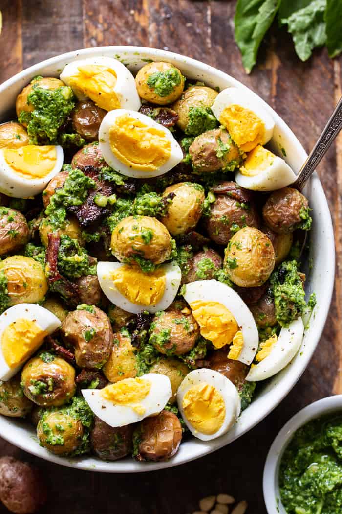 This pesto roasted potato salad is a super tasty twist on your traditional BBQ side dish.  Baby potato are roasted to bring out all the flavor and tossed with a dairy-free, Whole30 compliant pesto plus crispy cooked bacon and chopped eggs.  It's perfect served at room temperature or slightly warm.
